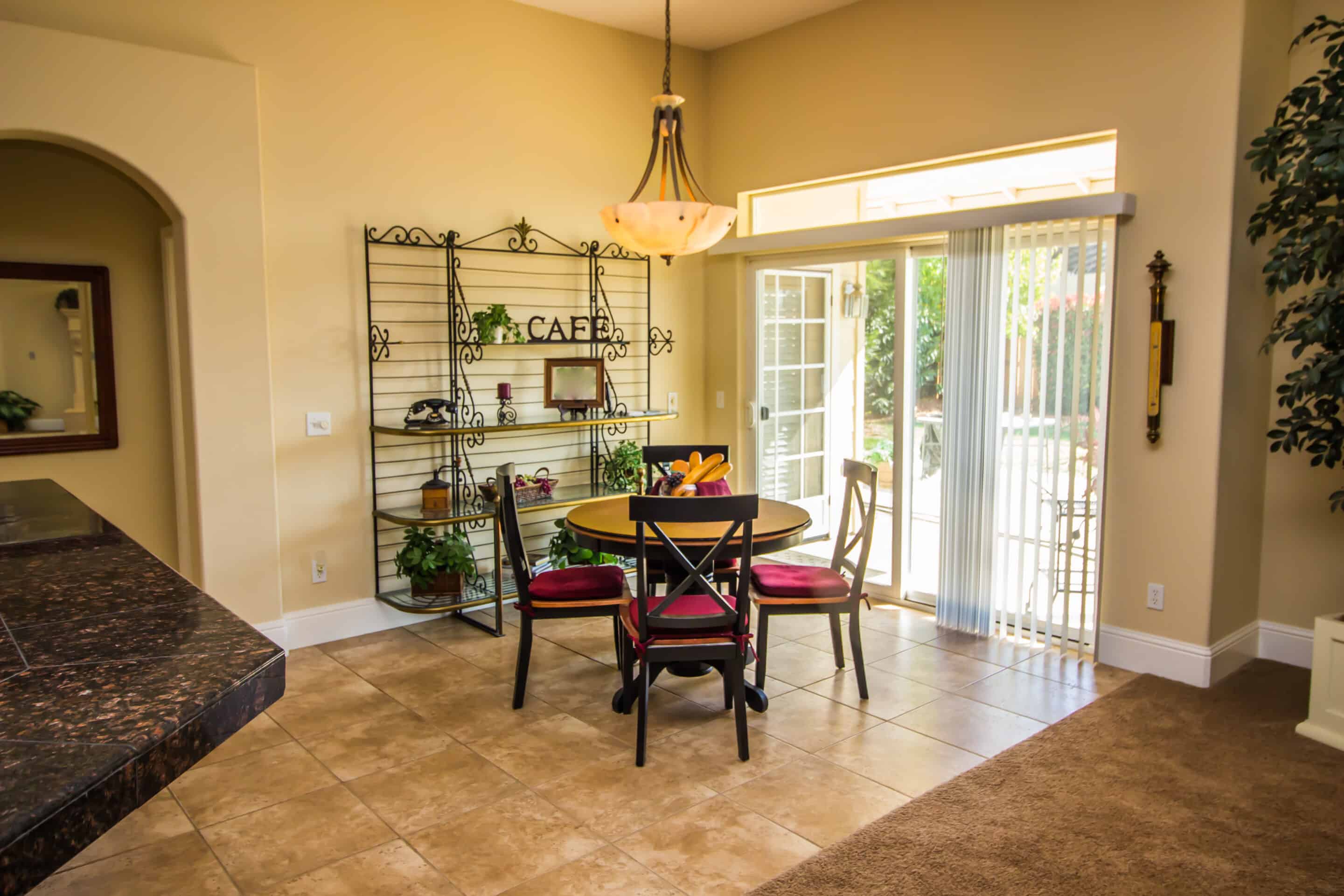 Antique Bakers Rack In Eating Area With Blinds on Sliding Door.