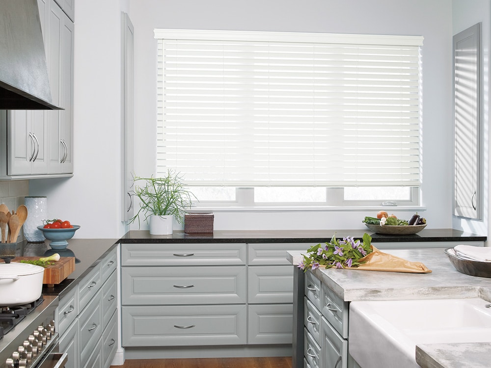 Faux wood blinds filtering in natural light into a modern looking kitchen.
