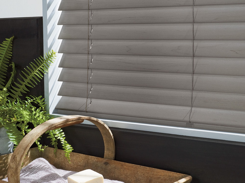 Faux-wood blinds filtering in light into charcoal and white painted room.