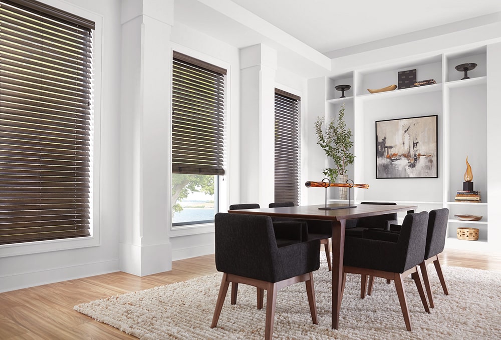 3 sets of faux wood blinds blocking out the light in a dining room.