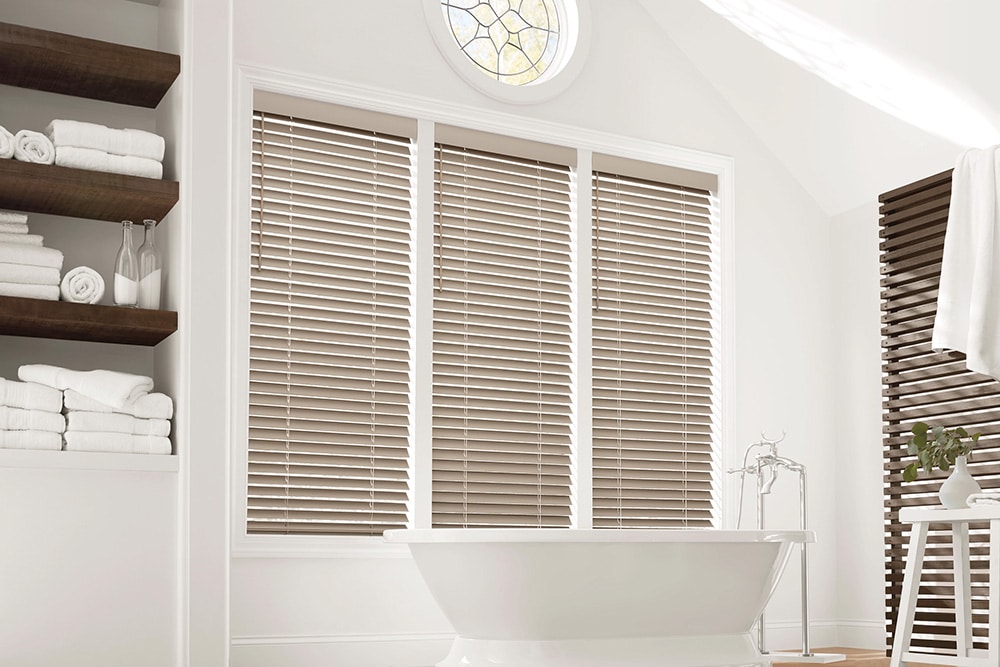 Faux wood blinds filtering in light into a beautifully designed bathroom.