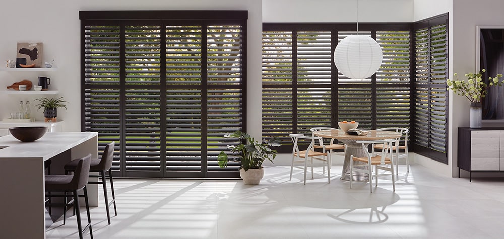 Custom made shutters filtering in light into a kitchen and dining area.