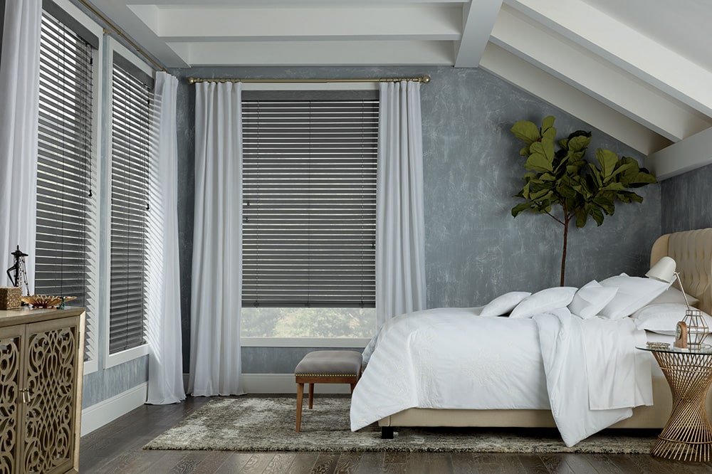 Custom made wooden shutters, filtering in light into a rustic bedroom.